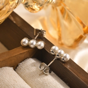 Elegant 3-pearl copper studs with white gold plating on luxury wooden jewelry box