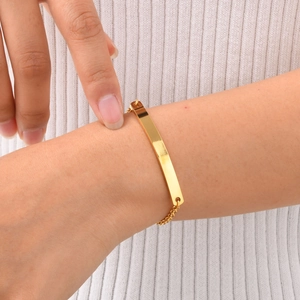 Macro detail of a minimalist gold bar bracelet on wrist with fine link chain texture