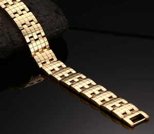 Macro shot of polished gold stainless steel bracelet with textured links and sleek reflection