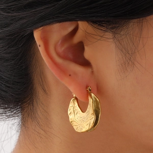 Golden irregular embossed C-shape hoop earrings with vintage texture worn by a model