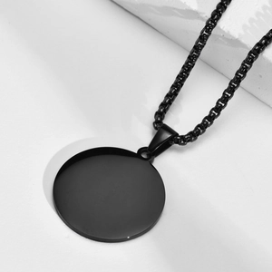 Gros plan d'un pendentif boussole noir en acier inoxydable sur un socle en pierre