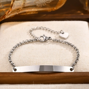 Close-up of a silver stainless steel ID bar bracelet with a heart charm in a gift box