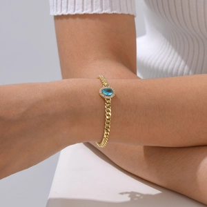 Detailed view of a gold-plated Cuban chain bracelet featuring a blue zircon centerpiece
