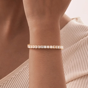 Detail of gold tennis bracelet with emerald cut cubic zirconia on a wrist