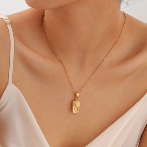 Gold stainless steel necklace with rectangular initial A pendant on a model