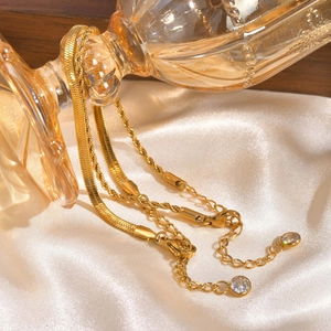 Détail du bracelet double couche en acier doré avec chaîne serpent et pendentif zircon