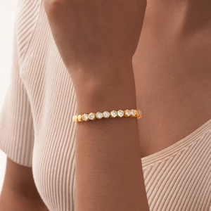 Detail of a gold geometric hexagonal link bracelet with zircon stones on a model wrist