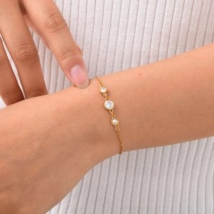 Elegant gold stainless steel cross chain bracelet with three white zircons on female wrist