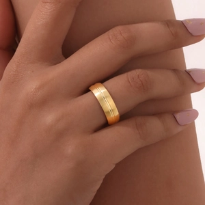 Bague minimaliste en acier doré avec rainure centrale portée sur main avec manucure