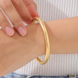 Detail of 14K gold plated flexible snake bone bracelet with spiral texture on wrist
