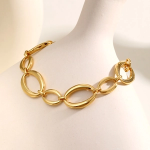 Detailed view of polished golden stainless steel oval link chain on white stand