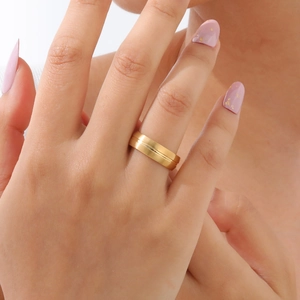Détail d'une bague minimaliste en acier inoxydable doré avec rainure centrale au doigt