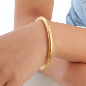 Polished 14K gold-plated stainless steel bangle with fine snake-bone spiral texture on wrist