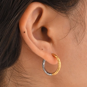 Détail de créoles bicolores avec motif losanges en or et argent portées par un mannequin