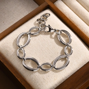 Détail d'un bracelet en acier inoxydable à maillons ovales sur support en lin beige