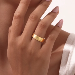Bague large minimaliste en acier inoxydable doré avec rainure horizontale portée au doigt