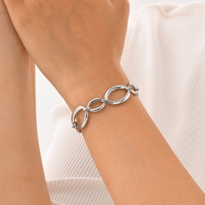 Close-up of a silver stainless steel oval link bracelet worn on a female wrist