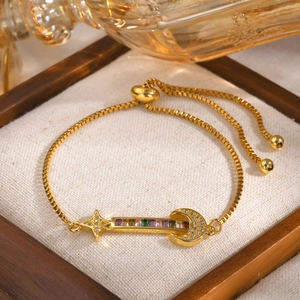 Détail du bracelet réglable doré avec zircons colorés sur un coussin blanc élégant