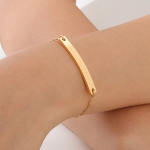 Close-up of a minimalist gold curved bar bracelet worn on a woman's wrist