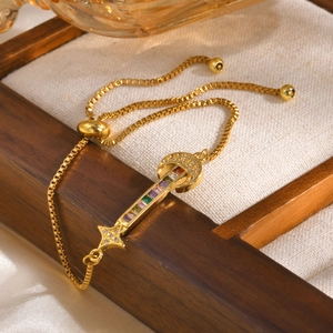Détail du bracelet ajustable en chaîne dorée avec pendentif clé aux pierres multicolores