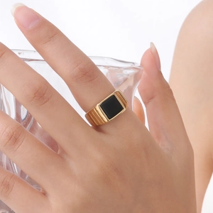 Vue détaillée d'une bague dorée avec agate noire et gravures latérales sur un mannequin