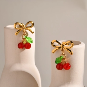 Boucles d'oreilles nœud doré avec pendentifs cerises rouges et feuilles sur pots blancs