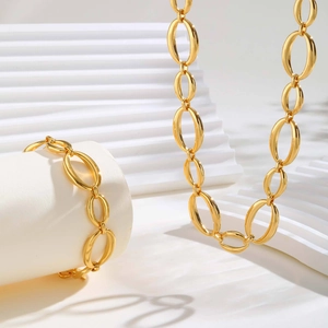 Polished golden oval link necklace and bracelet set displayed on a white display stand