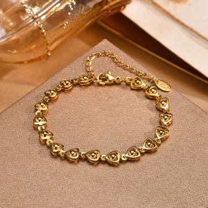 Detailed macro shot of a gold heart link bracelet featuring K18 stamp and lobster clasp