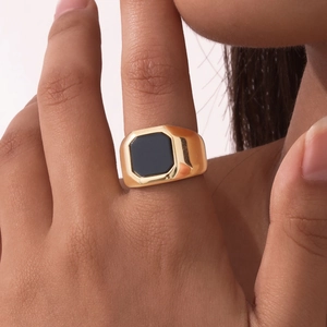 Gros plan détaillé d'une bague large en acier doré avec pierre d'onyx noire octogonale