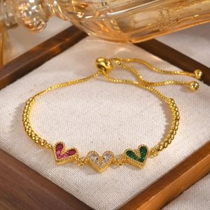 Détail d'un bracelet doré ajustable avec des zircons en forme de cœur tricolores