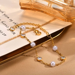 Dettaglio del bracciale dorato con perle bianche, zirconi, chiusura a moschettone ed estensione