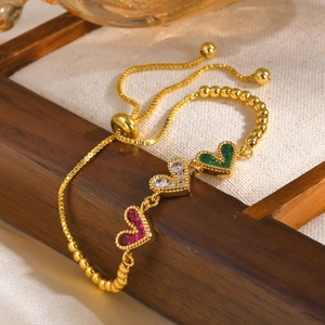 Détail d'un bracelet ajustable en or avec des zircons en forme de cœur rouges, blancs et verts