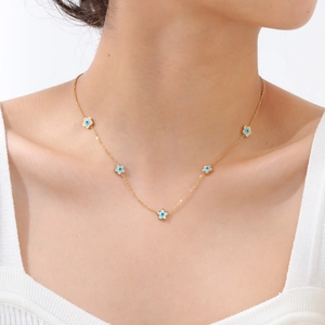 Dettaglio della collana dorata con fiori in smalto bianco e charms occhio blu