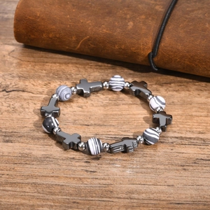 Close-up of black and white striped bead bracelet with metallic hematite cross on a desk