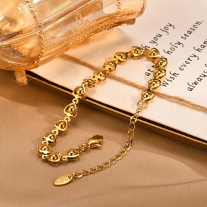Elegant gold stainless steel bracelet featuring hollow heart links with golden spheres