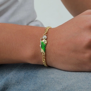 Detailed view of Saint Jude gold Cuban link bracelet with green enamel on male wrist