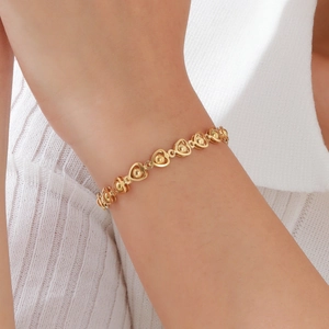 Elegant gold heart link bracelet with small metal beads worn on a woman's wrist