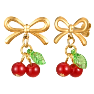 Boucles d'oreilles nœud doré avec cerises rouges et feuilles vertes sur fond blanc