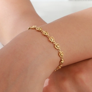Close-up of gold stainless steel heart chain bracelet with beads on a wrist