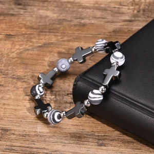Close-up of cross charm and striped beads on a vintage metallic beaded bracelet