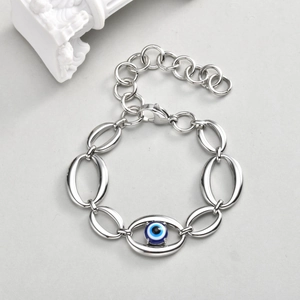 Macro shot of large oval stainless steel chain links and blue evil eye charm detail