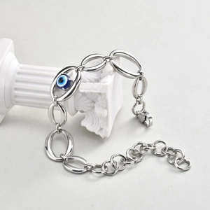 Detailed shot of silver steel chain bracelet with blue evil eye bead on a white pillar