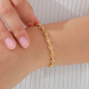 Golden heart-shaped chain bracelet with spherical link details on female wrist