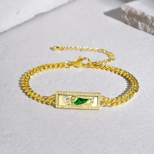 Macro shot of gold Cuban chain bracelet with green enamel religious pendant and zircons