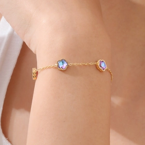 Elegantes goldenes Gliederketten-Armband mit irisierenden Blumenanhängern am Handgelenk