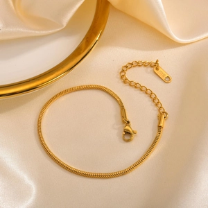 Minimalist golden square snake chain bracelet with 18K engraving on satin background