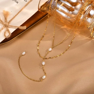 Vue détaillée du collier doré multicouche orné de perles sur un support en tissu texturé