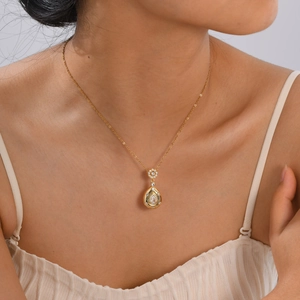 Élégant collier doré avec pendentif goutte d'eau serti de zircon porté par un mannequin