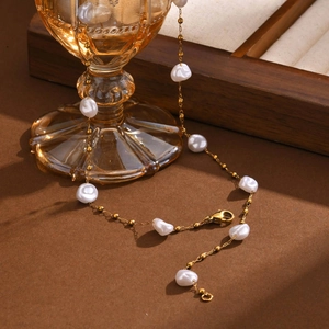 Elegant gold stainless steel Y-necklace with baroque pearls on an amber glass
