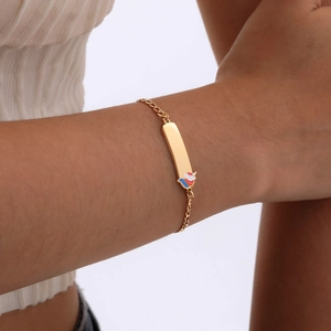 Close-up of gold stainless steel kids bracelet with colorful unicorn charm on a nameplate
